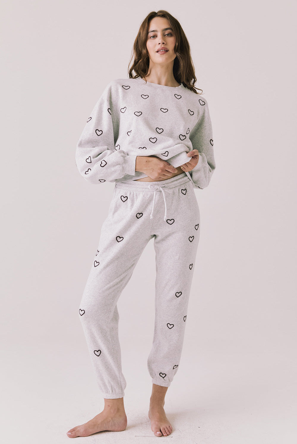 Woman wearing a light gray pajama sweathirt with heart print