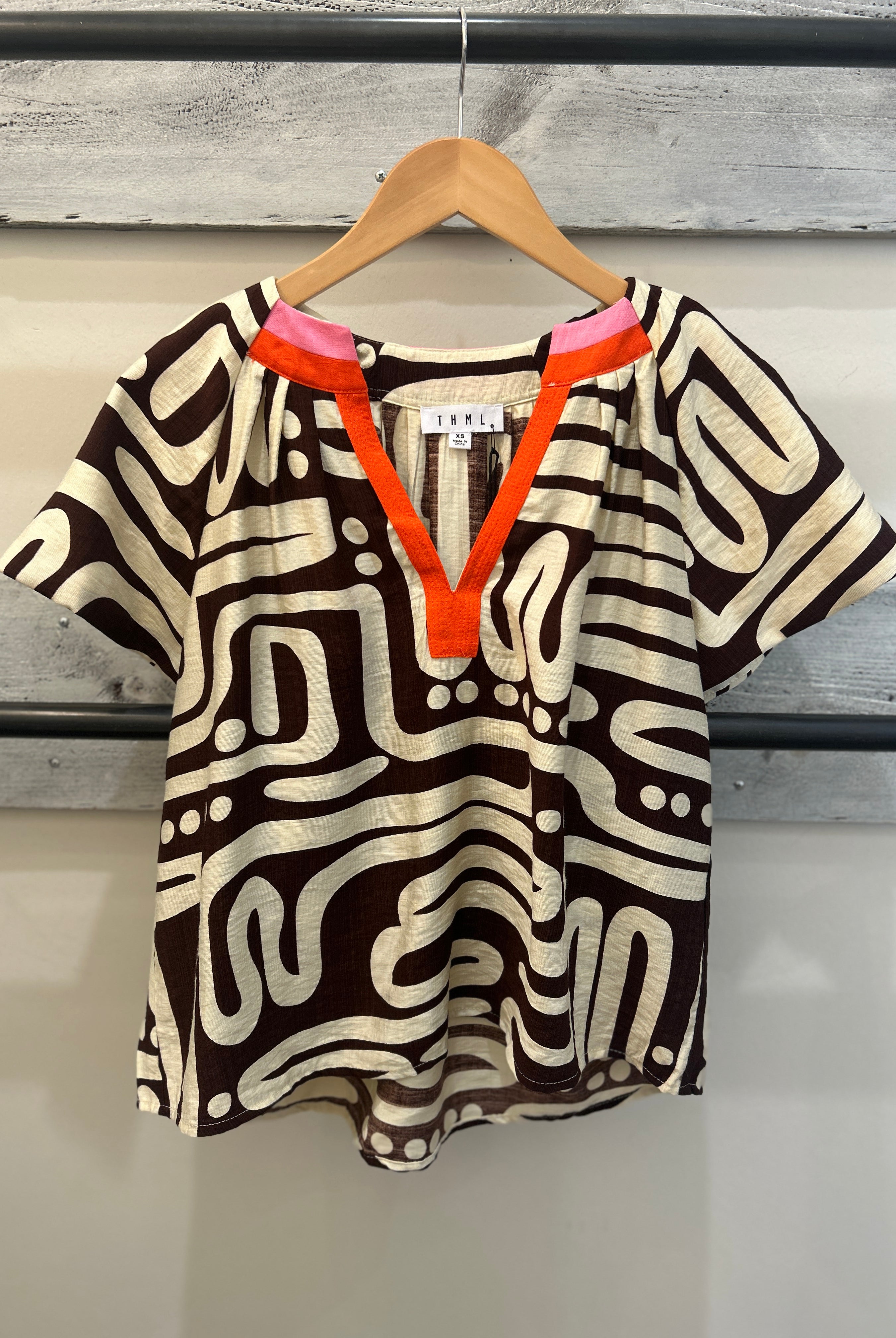 Patterned black and cream top, with red and pick accents at the collar.