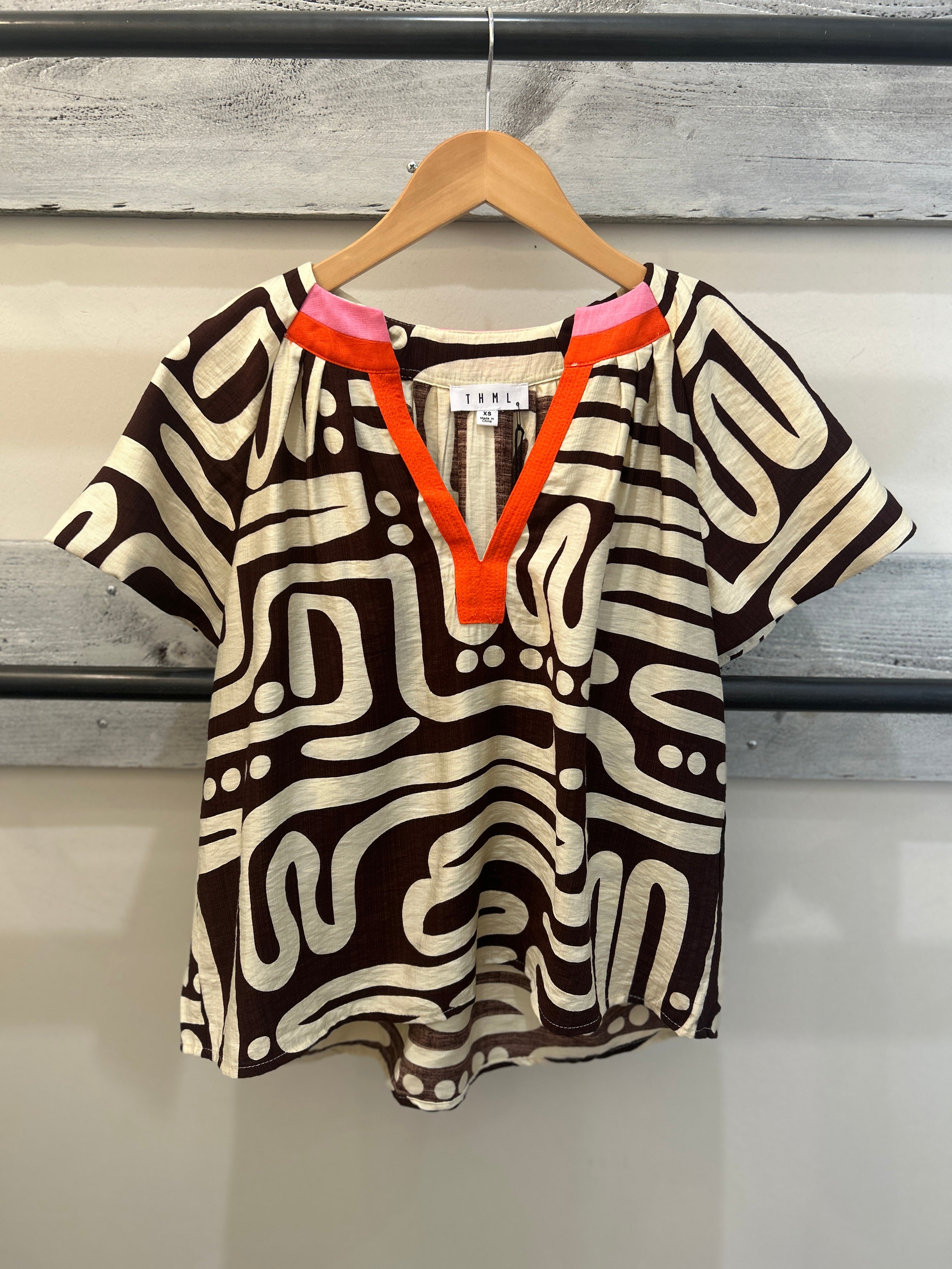 Patterned black and cream top, with red and pick accents at the collar.