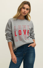 Woman wearing a gray sweatshirt with 'LOVE' printed in red.