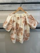 beige top with brown floral pattern
