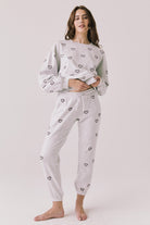 Woman wearing a light gray pajama set with heart patterns .