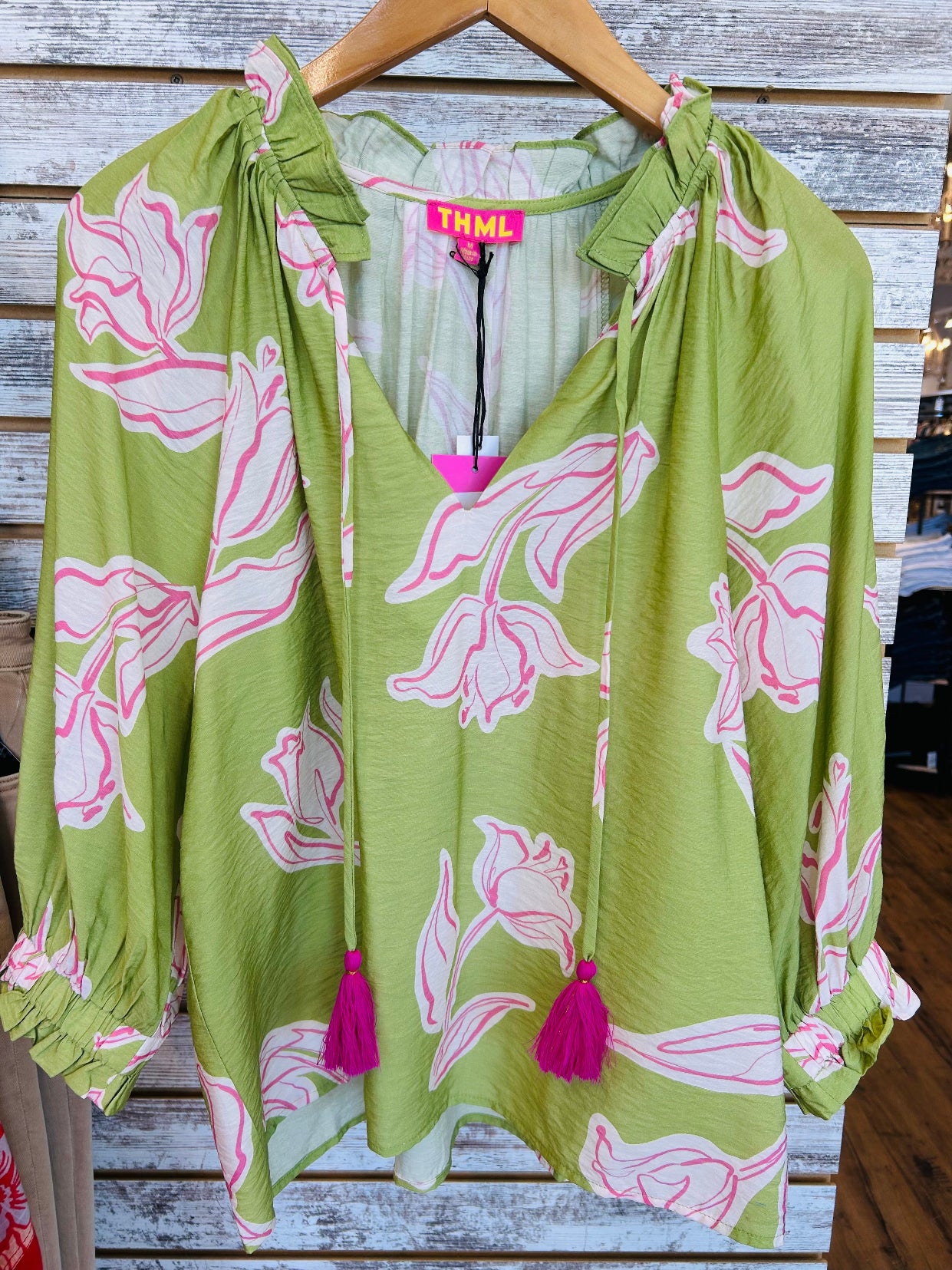 Green blouse with pink floral patterns and tassels .