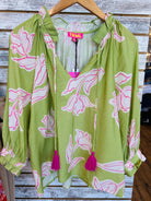 Green blouse with pink floral patterns and tassels .